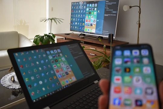 Lo schermo di un iPhone si riflette su un laptop e una TV allo stesso tempo