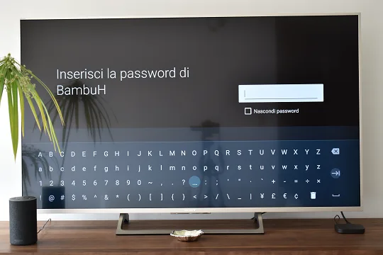 L'immagine mostra la richiesta di inserire la password della rete Wi-Fi selezionata, con una tastiera virtuale sullo schermo del televisore.