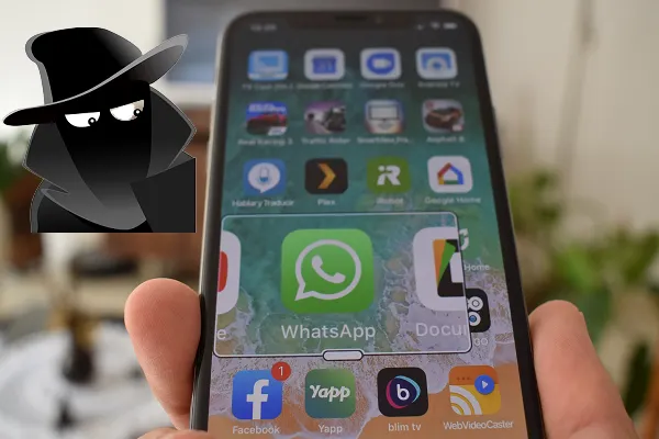 Immagine di un uomo mascherato che spia uno smartphone con l'icona di WhatsApp in primo piano