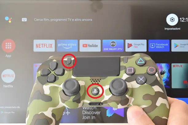 Controller PS4 con pulsanti per metterlo in modalità di accoppiamento. Dietro una Smart TV Android TV