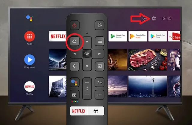 Pulsante Home su un telecomando Smart TV Android TCL. Sullo sfondo una TV TCL